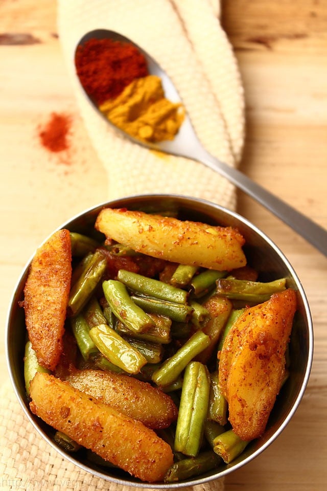 aloo beans recipe served in a steel bowl on a cream colored cotton woven napkin.