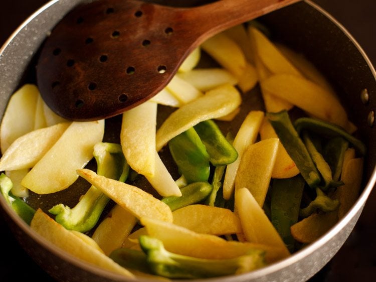 sautéing potatoes and capsicum to make aloo shimla mirch ki sabji 