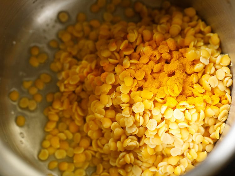 lentils and turmeric added in a cooker to make sambar recipe