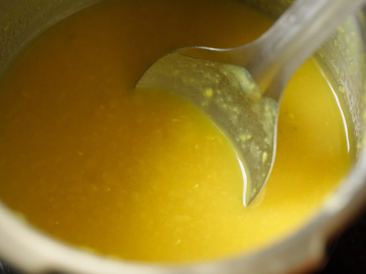 lentils cooked well and being mashed with a spoon to cook sambar recipe