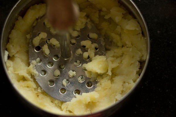 mashing aloo in a bowl.