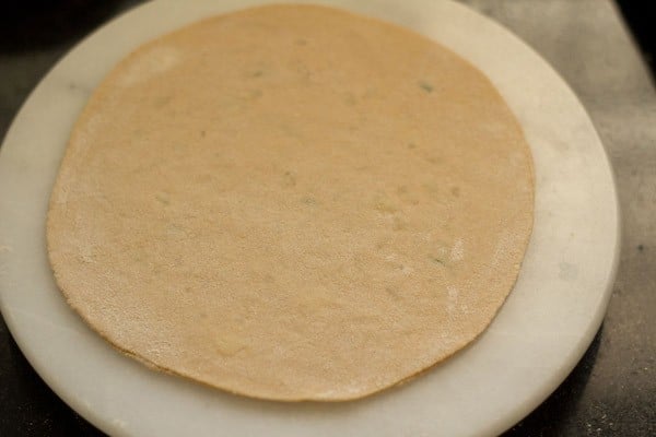 rolled aloo paratha on board ready to be roasted.