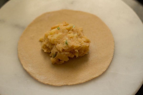 placing stuffing on a single round of paratha dough.