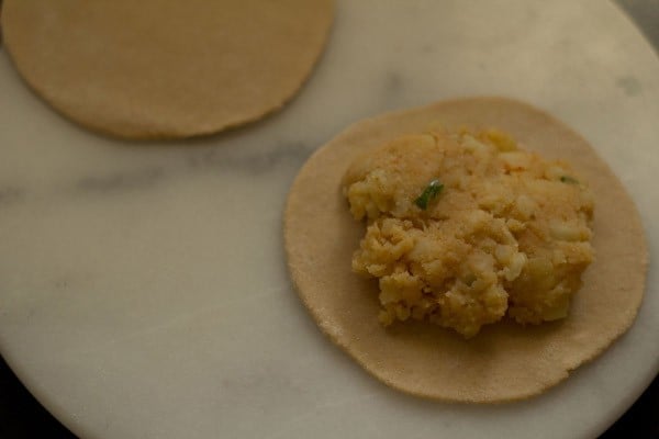 placing aloo stuffing on rolled paratha using the two disc method.