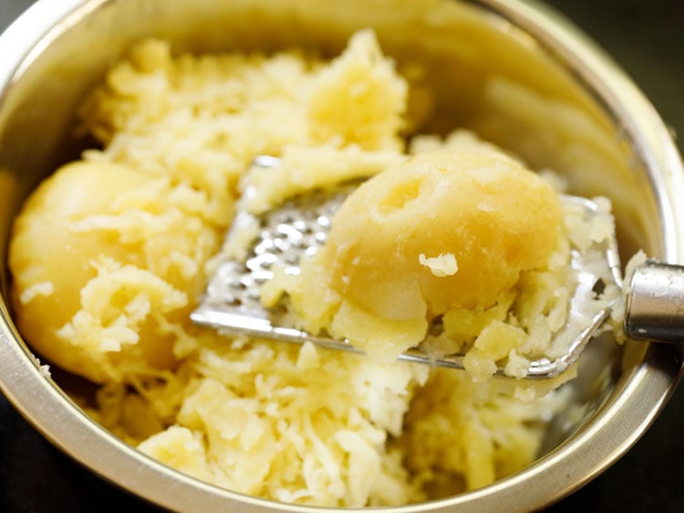 warm potatoes peeled and then being grated.