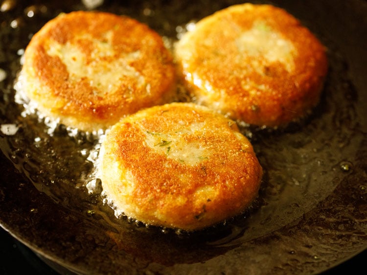 aloo tikki flipped and frying the second side.