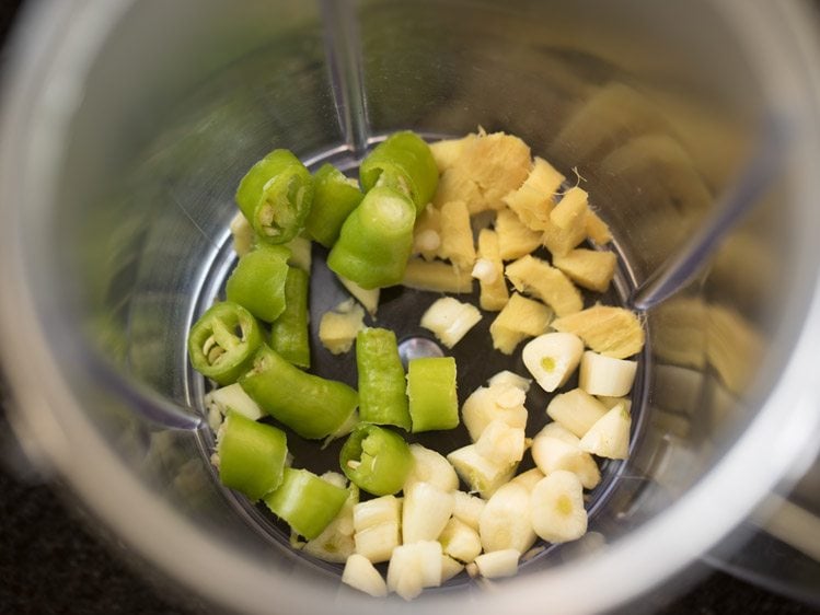 taking green chiliies ginger garlic in a grinder