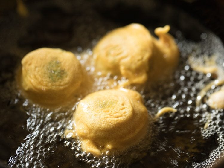 frying and turning batata vada in hot oil