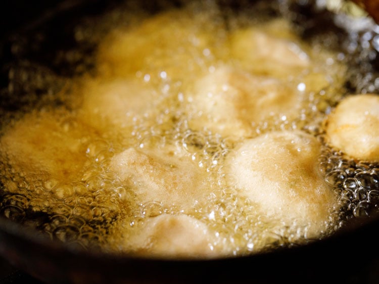 gulgule being fried in oil in a kadai.