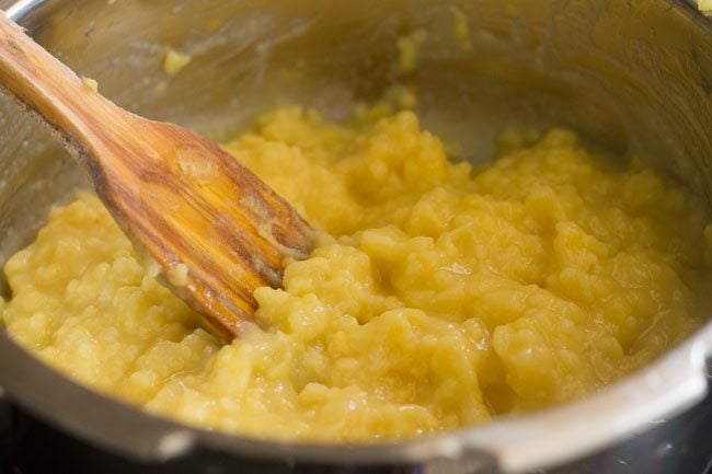 lentils being mashed with wooden spoon