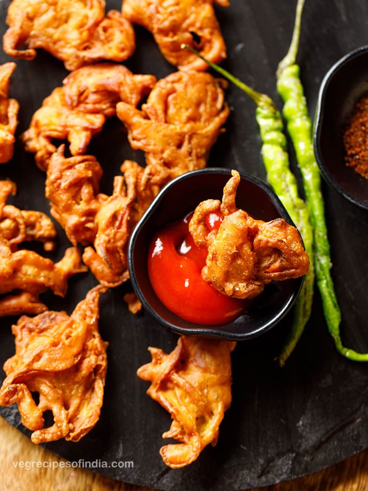 onion pakoda served on a plate with tomato sauce