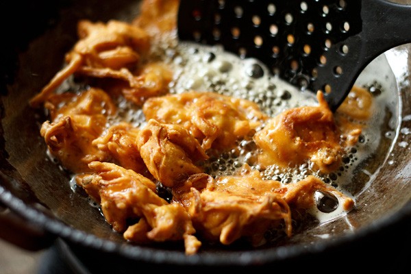 frying onion pakora till crisp and golden in oil