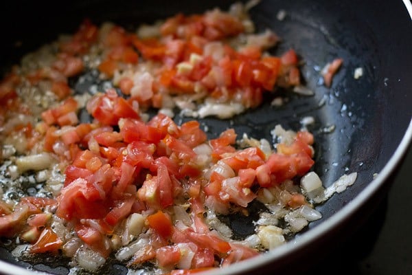 chopped tomatoes added to aromatics in pan