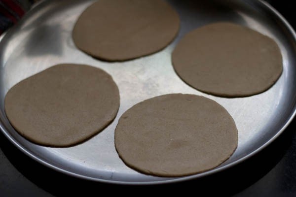 4 rounds of puri dough on a plate waiting to fry.