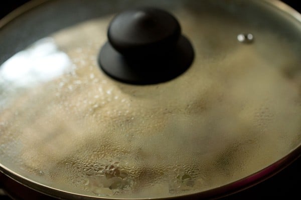 pan covered with glass lid for steaming the upma