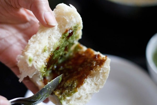 green chutney and sweet chutney spread on the sliced pav