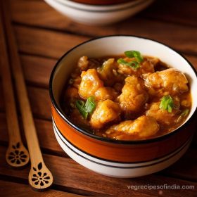 gobi manchurian gravy in a ceramic bowl placed next to two wooden chopsticks