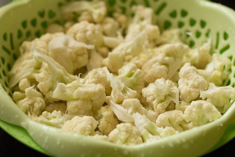 blanched cauliflower florets in a green strainer