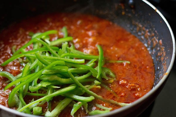 thinly cut capsicum slices added to kadai masala gravy to make kadai paneer recipe