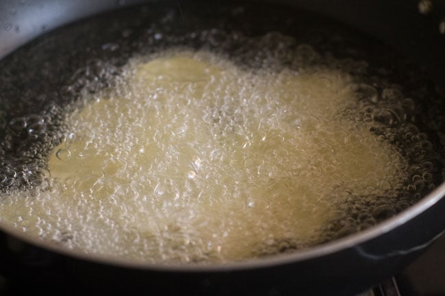 frying potato slices in oil in a kadai