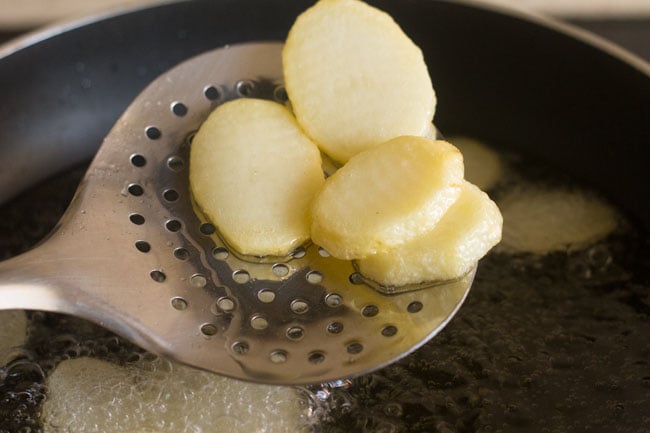 slightly fried potato slices in a slotted spoon