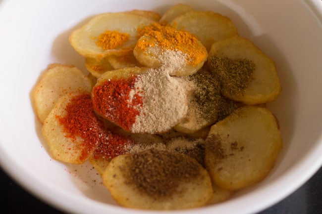 adding spices to fried potato slices