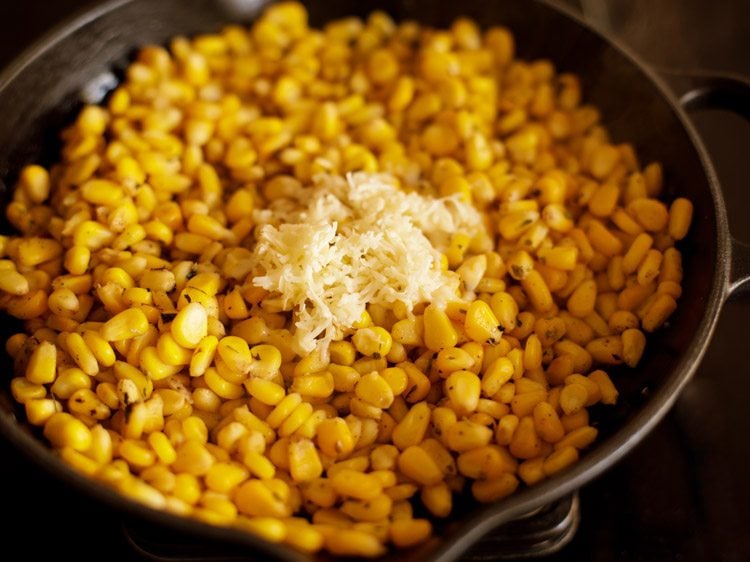 adding grated cheese to corn kernels mixture