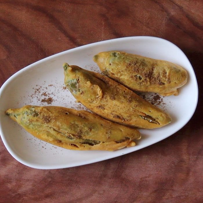 sprinkle chaat masala on mirchi pakora placed in a plate