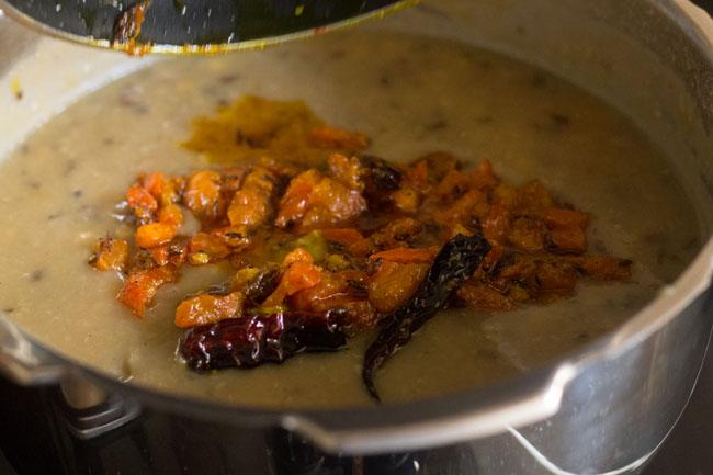 adding tempering mixture to cooked lentils