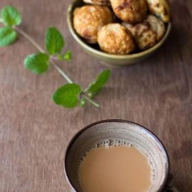 mint tea in a ceramic cup with a mint stem and some snacks in the background