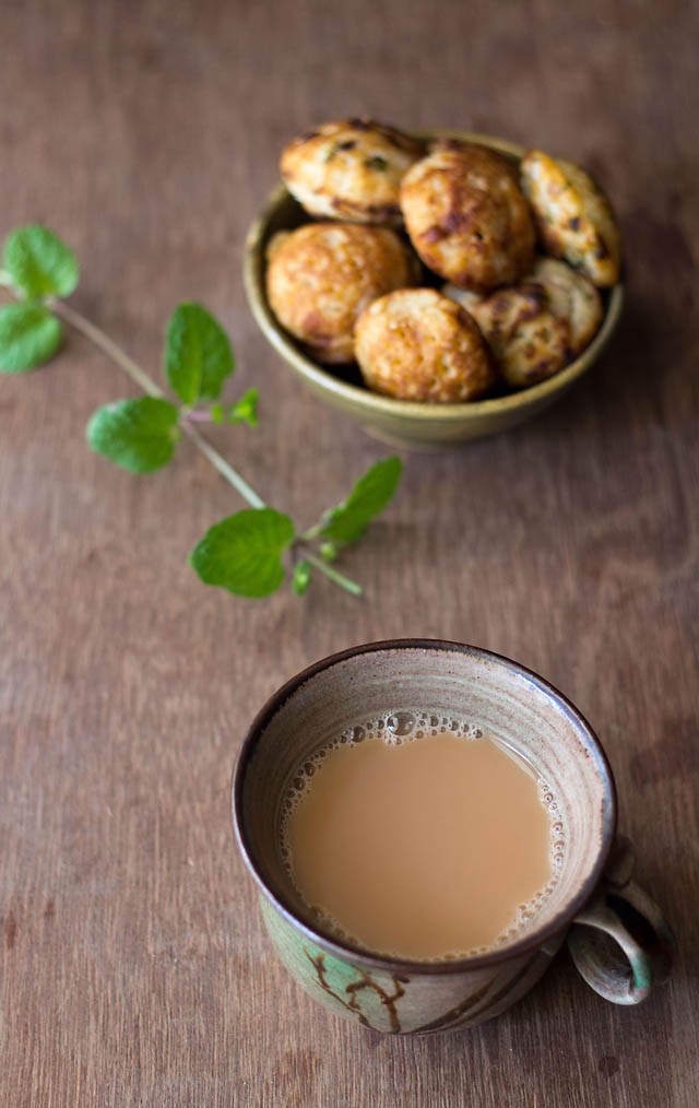 mint tea in a ceramic cup with a mint stem and some snacks in the background