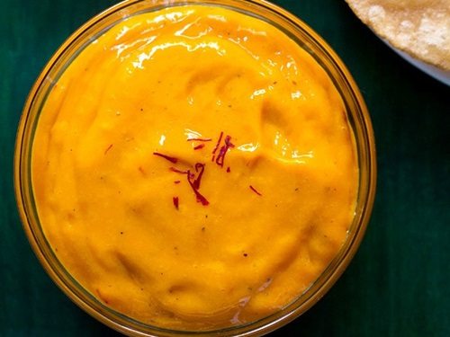 top close up shot of aamras in glass bowl with a few saffron strands on top