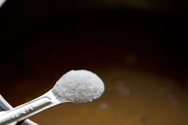 salt being added with a silver measuring spoon