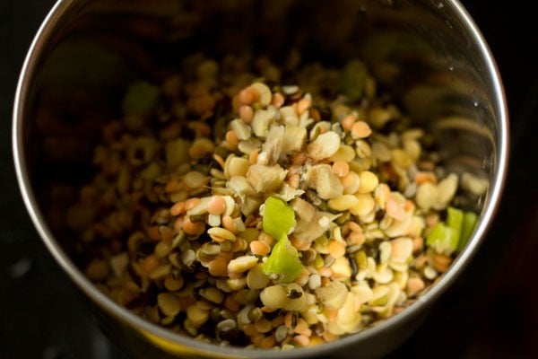 mixed lentils added to grinder jar with herbs and spices