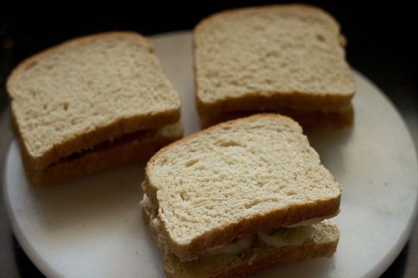 covering tomato cucumber sandwich with second bread slice