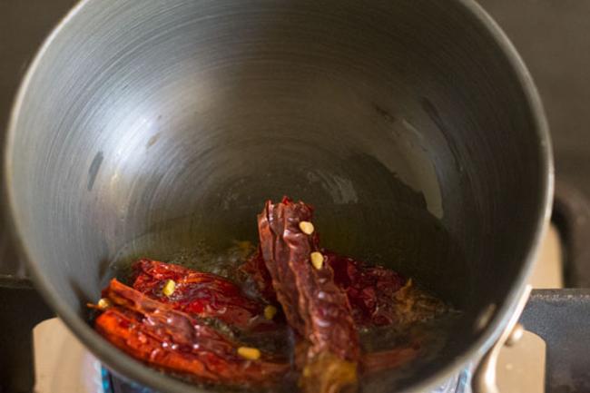 adding dried red chilies and fenugreek seeds to ghee