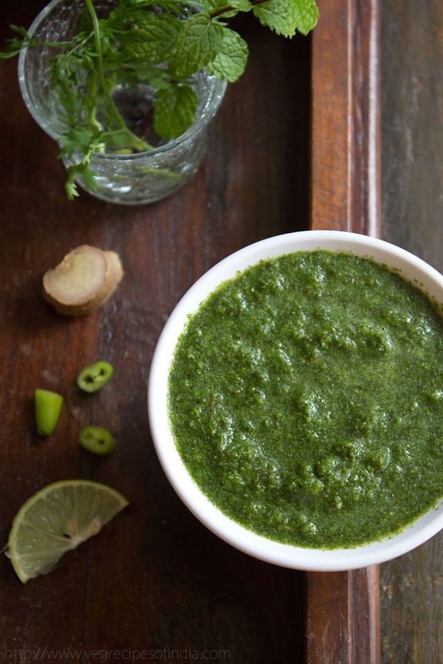 mint coriander chutney in a white bowl on a wooden board