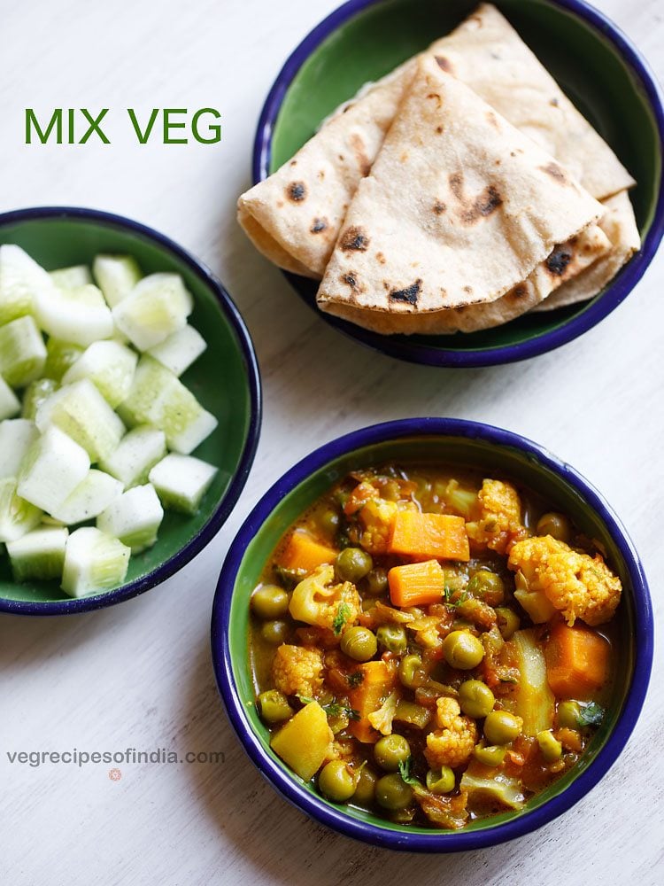 overhead shot of mix veg curry recipe in a blue rimmed bowl on a white table