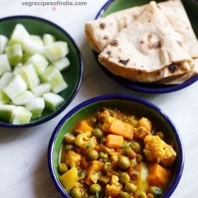 overhead shot of mix veg curry recipe in a blue rimmed bowl on a white table