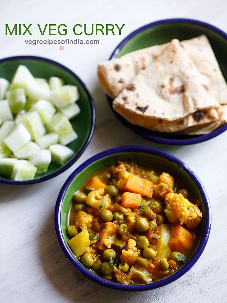 overhead shot of mix veg curry recipe in a blue rimmed bowl on a white table