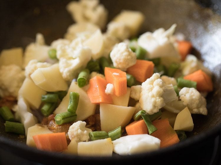 carrots, potatoes, green beans and cauliflower added to tomato onion masala