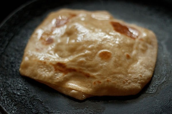 applying ghee on second side of paratha