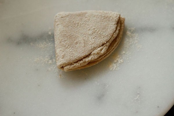 applying flour on rolled paratha