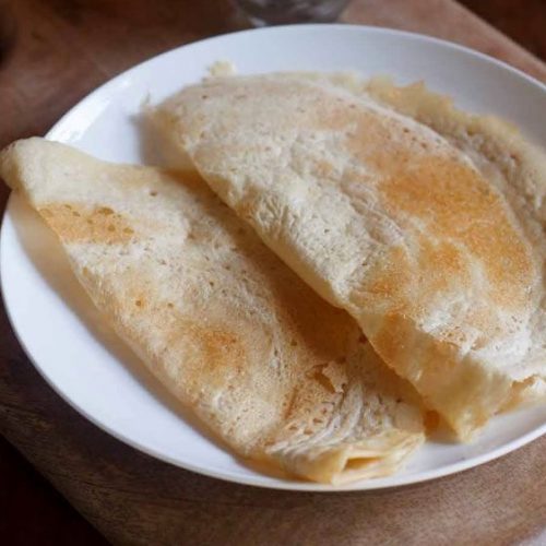 urad dal dosa on a white plate.