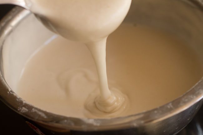 pouring urad dal batter in a vessel 