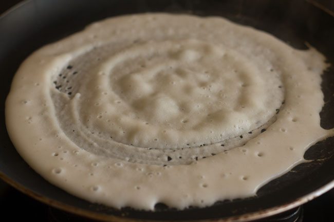 cooking urad dal dosa on hot tava