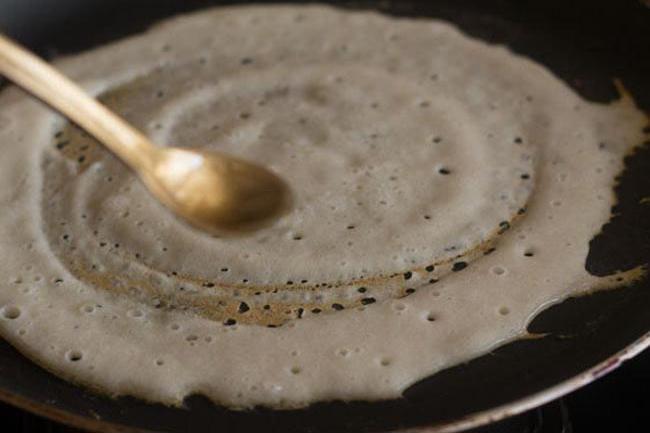 drizzling oil on edges and center of dosa