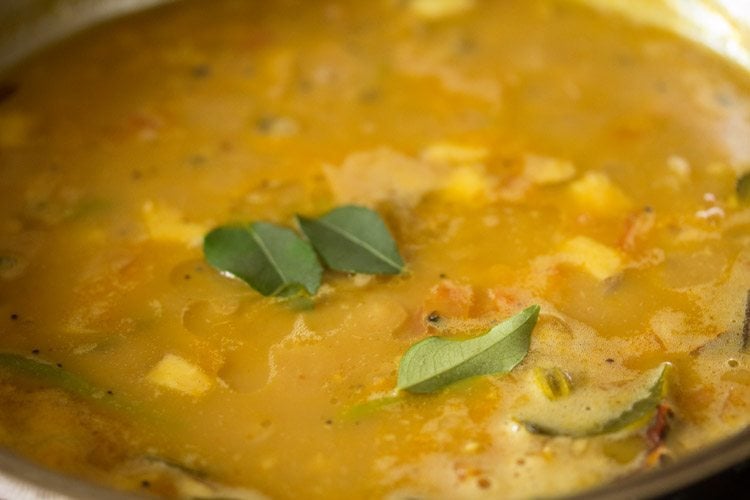 adding curry leaves and coconut oil to cooked vellapayar curry