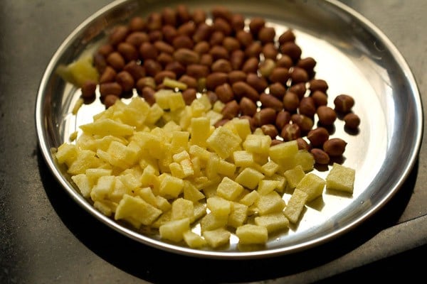 sautéed potatoes and roasted peanuts on a steel plate.