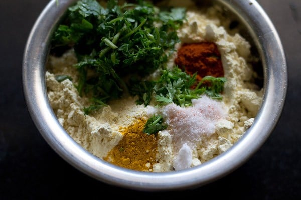 in a mixing bowl add gram flour coriander leaves and spices